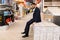 a buyer of a finishing goods store in a business suit sits on a stack of parquet boards