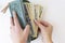 Buying for dollars. A woman`s hand holds a green wallet and counts out money. White background