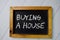 Buying a House text write on chalkboard isolated on office desk