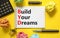 BYD build your dreams symbol. Concept words BYD build your dreams on white note on a beautiful yellow background. Black pen.