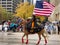 Bystanders watching Cowgirl Holding US Flag on Horse Back at Thanksgiving Parade