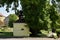 Bystrany, Czech republic - May 23, 2019: little chapel in shadow of big tree in centre of village in spring