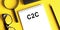 C2C abbreviation consumer to consumer written on notepad next to glasses, a pencil and a magnifying glass on a yellow background