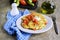 Cabbage fritters with green onions, tomatoes and mayonnaise on a white plate