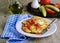 Cabbage fritters with green onions, tomatoes and mayonnaise on a white plate on a gray concrete background. Cabbage recipes