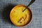 Cabbage soup with mixed sour cream and a metal spoon in a brown earthenware bowl