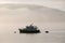 Cabin cruiser boat anchored offshore in the early morning fog at Spencer Spit State Park on Lopez Island, Washington, USA