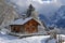 A cabin stands on a snow-covered mountain, surrounded by a wintry landscape, A quaint Swiss chalet in the Alps, AI Generated