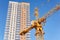 Cabin of tower crane and new block of flats on a background of blue sky