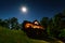 A cabin in the woods at night with the moon shinning