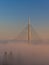 Cable bridge lit by sunshine above fog at sunrise near Ada in Belgrade