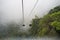 Cable car above green forest in misty clouds
