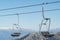 Cable car seats close-up with snow mountains at background.