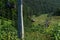 Cable car seats with people among coniferous trees in green forest on hill in mountains,