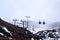 Cable cars and ski lifts going up and down snow blanketed slopes of the mountain while a snow storm building up. Mt