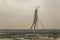 Cable-stayed bridge under construction over the Yamuna river in cloudy weather