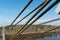 Cables and ropes of a suspension bridge close-up. Fixing the old bridge over the river. Rusty iron cables against a blue sky