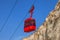 Cableway red cabin against bright blue sky and white chalk cliff.