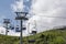 Cableway under the blue sky with white clouds and over the green grass