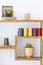 Cacti and colorful yarns on wooden shelves in scandi modern living room interior. Real photo