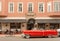 Cadillac cabriolet red car in vintage style parked past hotel with relaxing tourists