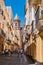 Cadiz SPAIN - 8 August 2022 - Street with people walking and with tiled tower and dome of San Lorenzo Parish church