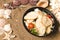 Caesar Salad with chicken fillet in black Food Delivery plastic bowl with sea shells and stars on Sand background