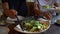 Caesar salad mixing in bowl giving to wife