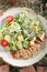 Caesar Salad with Sliced Chicken Fillet on Rustic Hay Background