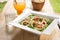 Caesar salad in White plate,Orange juice,Glass of water on wooden table.