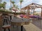 Cafe next to the beach. Tables and bar stools made from sawn wood, tents with soft, low mattresses, scattered multi-colored