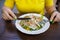 in a cafe at a table in front of a plate of dietary salad, a girl holds a fork and a knife in her hands