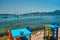 Cafe tableon beach in Adamantas town on Milos island with Aegean sea with boats in background