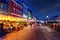 Cafes and Restaurants with illumination and colorful facades of old houses on the Nyhavn waterfront canal under the night sky with