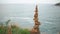 A cairn is stands on top of a cliff against the blue sea. Heap of stones close-up