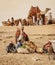 Cairo, Egypt - Dec. 2018: Egyptian boy feeding camels waiting for tourists on the Giza Plateau