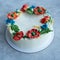 Cake with buttercream frosting decorated with buttercream flowers, Poppies, chamomile, cornflowers, spikelets of wheat, on gray