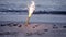 Cake fountain candle with sparks burning on sand on sandy beach on sea ocean
