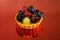 Cake with fresh bio fruits, grapes, raspberries, blackberries, side view photo, mirror red background