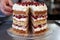 cake layers with cream and cherries being assembled