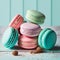 Cake macaron or macaroon stack on turquoise background, colorful mint and pink almond cookies, pastel colors