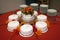 Cake place setting on round table with red table cloth and stacks of serving plates