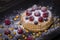 Cake with raspberries, blueberries, sea buckthorn sprinkled powdered sugar on a black plate