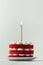 cake with red velvet sponge layers and white cream cheese filling decorated with lit golden candle. One year old