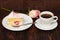 Cake slice and coffee cup with rose on wooden background