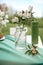 Cake with some cups on picnic table decorated with flowers, candles, vase in green field