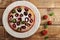 Cake with strawberries in plate on wooden background