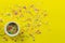 Cake topping prinkles on bright yellow background with little white bowl with various type of coloured sprinkles at bottom  and