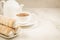 Cake a tubule with white cream and tea cup/ tea drinking with cream cakes on a white marble background. Copy space