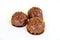 cakes in the shape of a ball drenched in milk chocolate with nuts on a white background